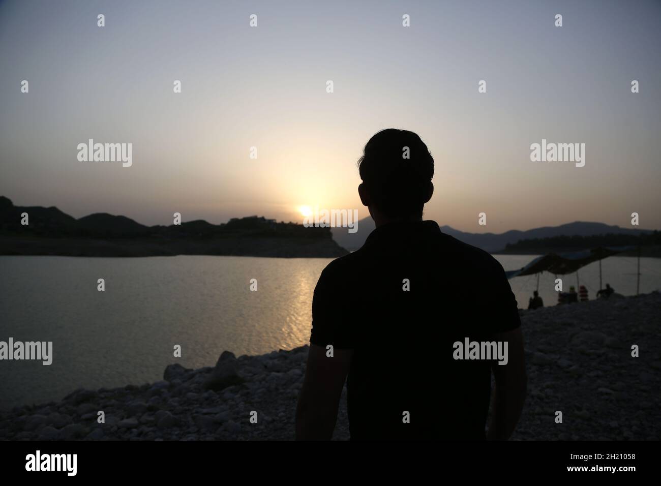Khanpur. 19th Oct, 2021. Photo taken on Oct. 19, 2021 shows a man enjoying the view of sunset at Khanpur Lake in Khanpur of Pakistan's northwestern Khyber Pakhtunkhwa province. Credit: Ahmad Kamal/Xinhua/Alamy Live News Stock Photo