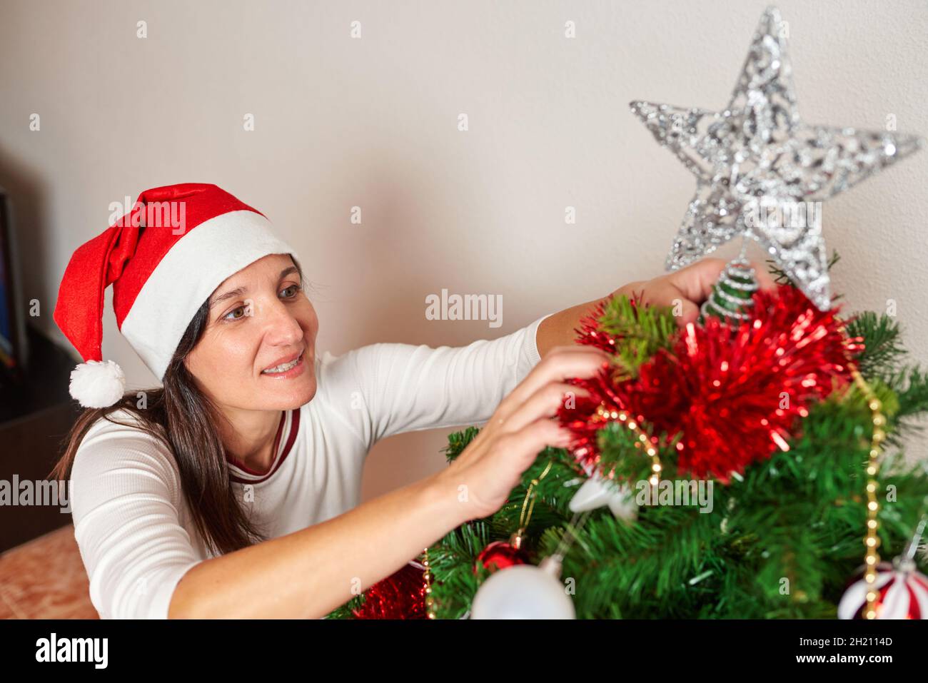 woman placing a star on top of the christmas tree Stock Photo Alamy