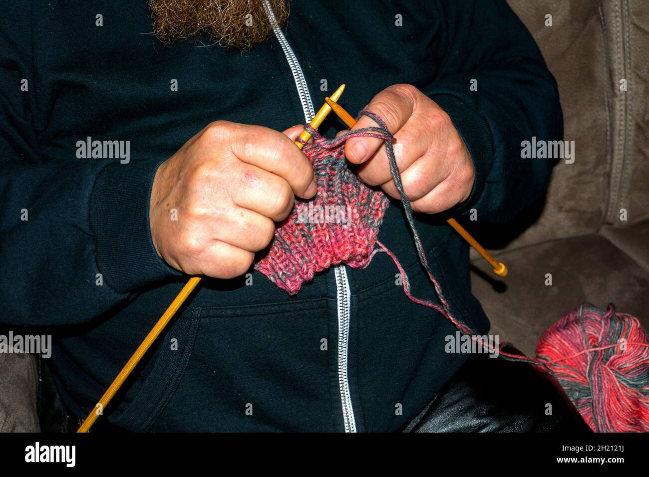 Ein Mann strickt einen Schal Stock Photo