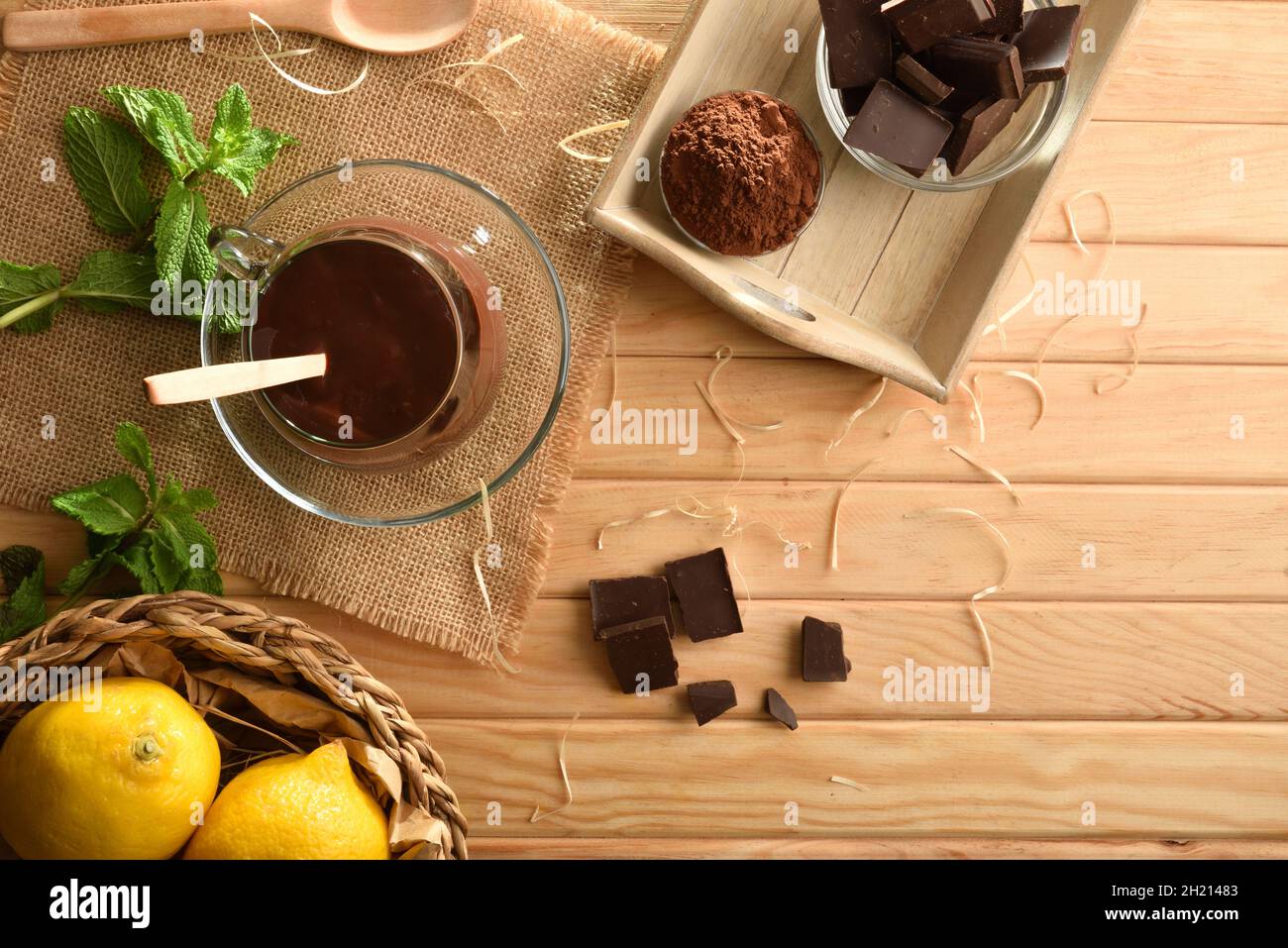 Hot chocolate cream in glass cup on wooden slat table with piece and chocolate powder. Elevated view. Horizontal composition. Stock Photo