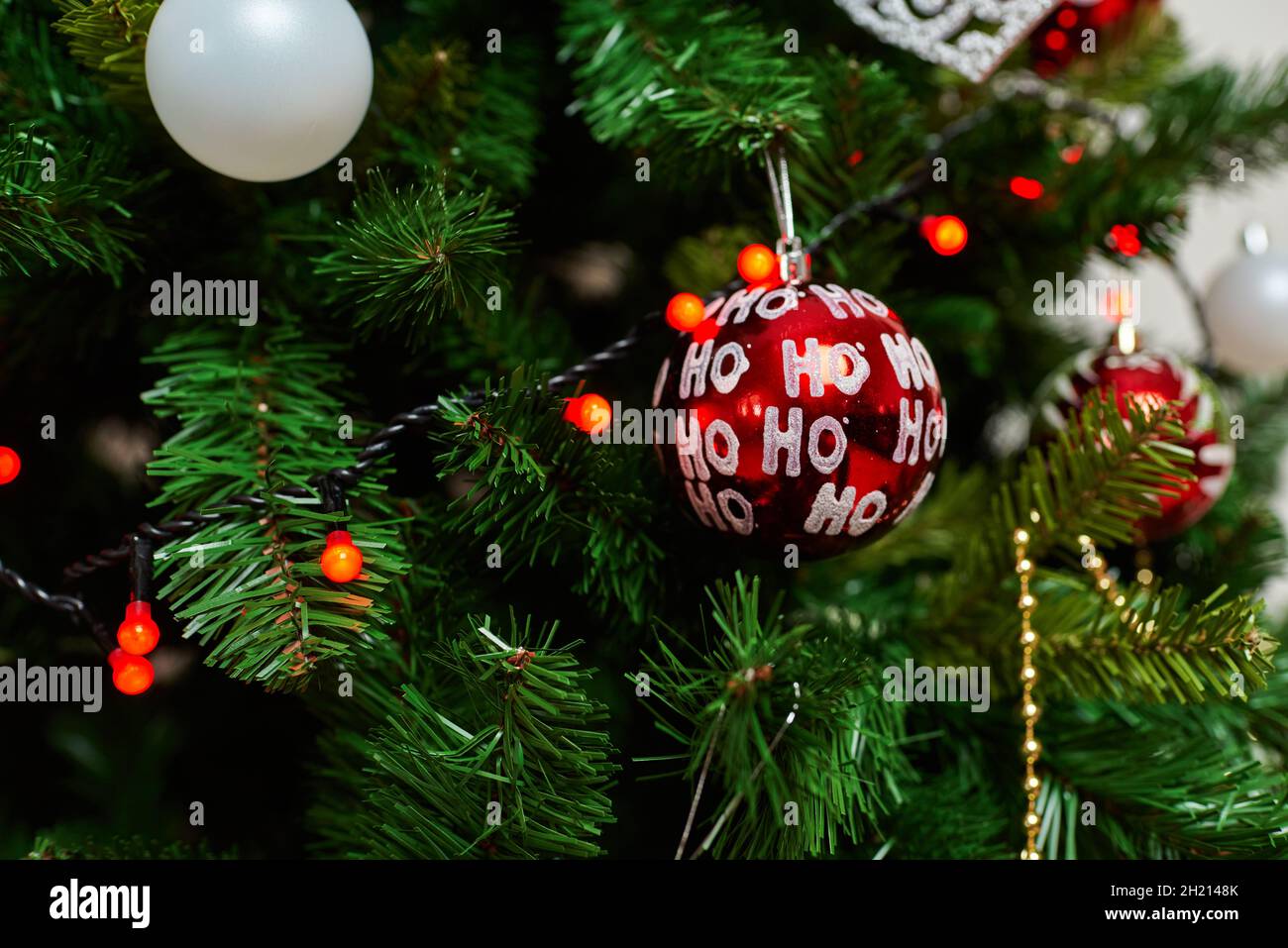 Traditional artificial Christmas tree with red ball ornament with glowing lights Stock Photo