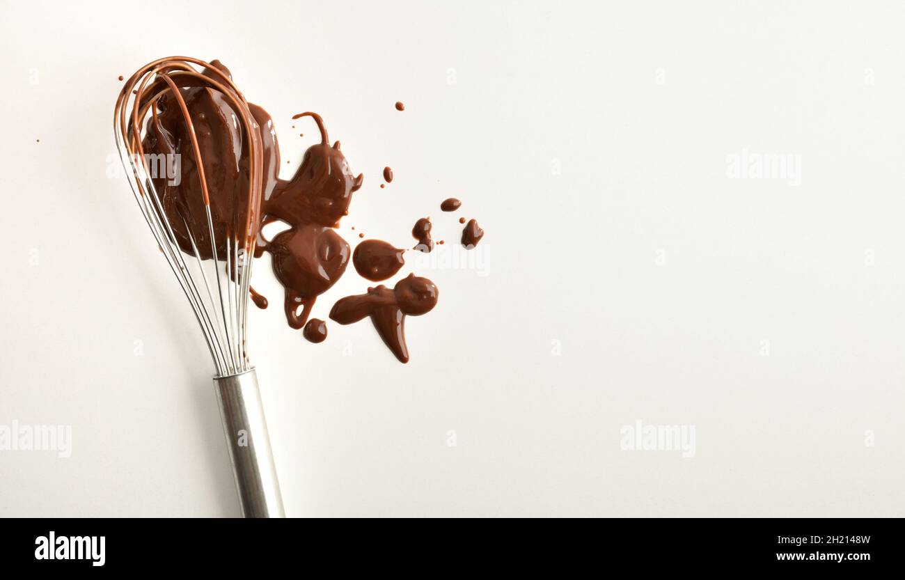 Background with chocolate stained wooden kitchen spoon on white table. Top view. Stock Photo