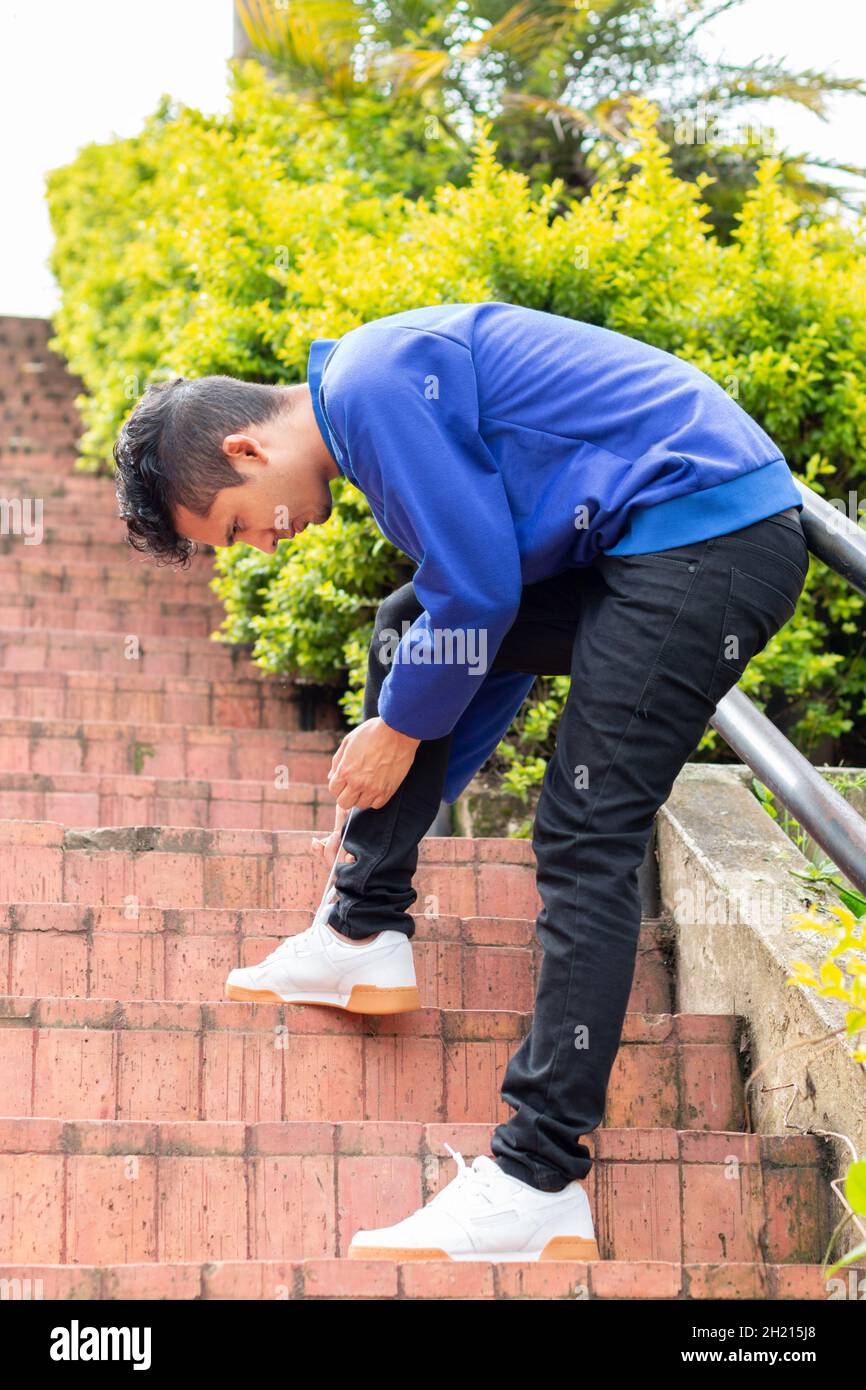 Man tying his shoelaces on a staircase. Blue and orange colors. Stock Photo