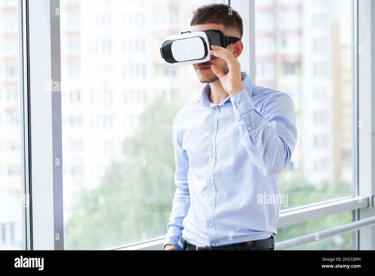 Young man wearing virtual reality glasses in modern interior design ...