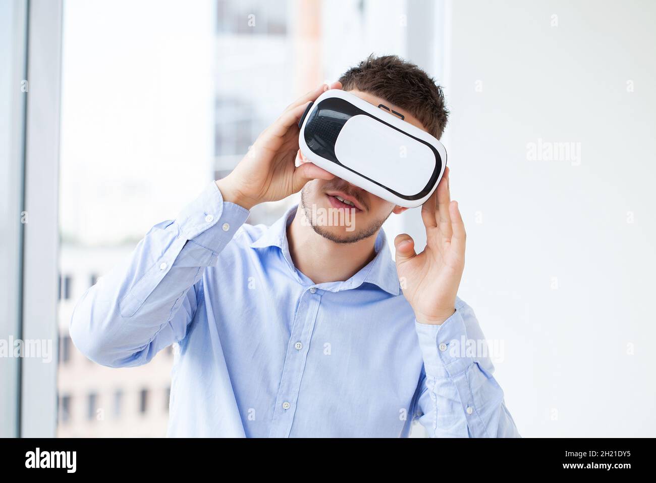 Young man wearing virtual reality glasses in modern interior design ...