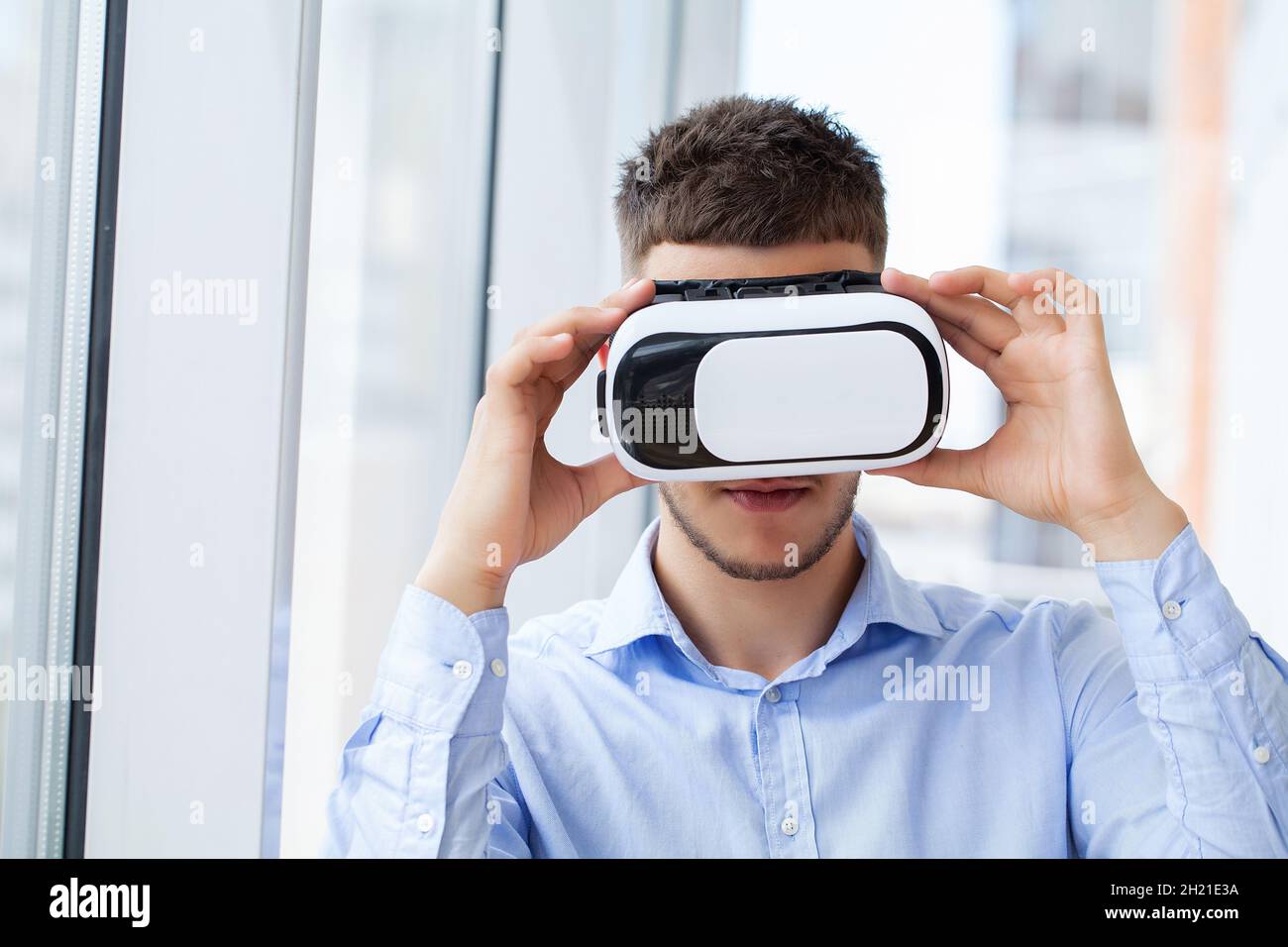 Young man wearing virtual reality glasses in modern interior design ...