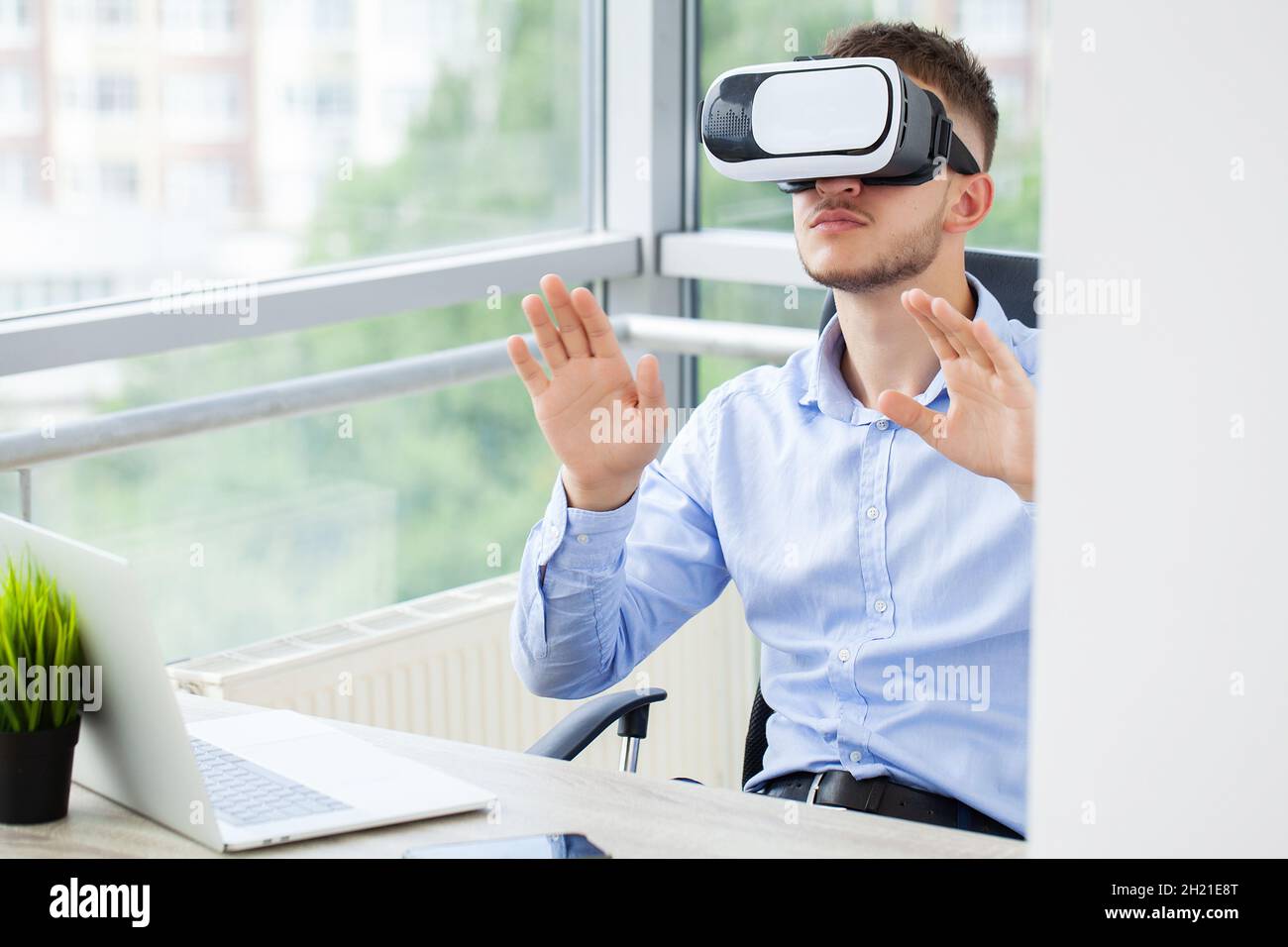 Young man wearing virtual reality glasses in modern interior design ...