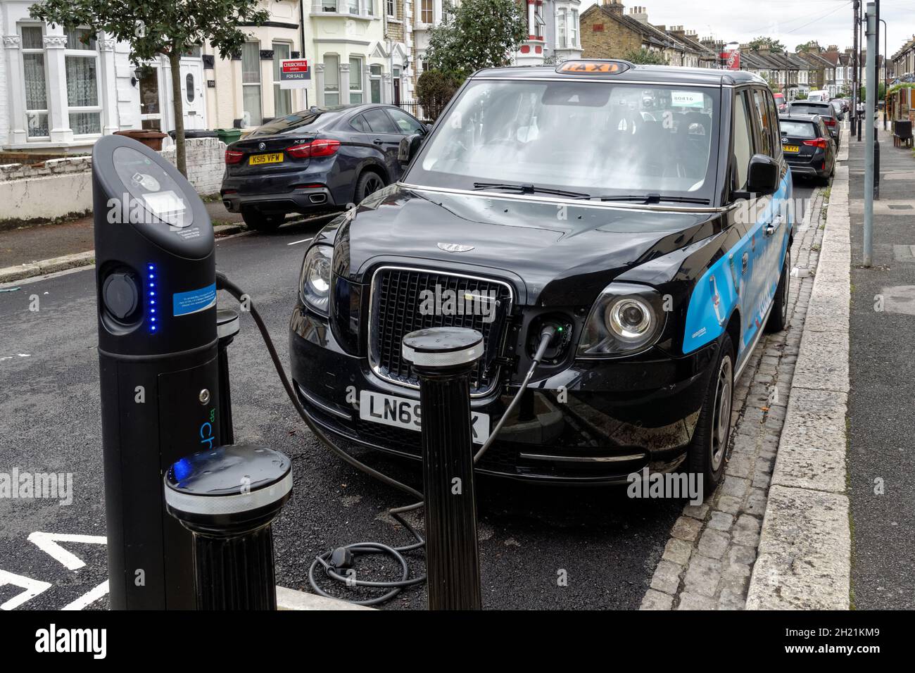 New electric black cab charging at charging point in London England United Kingdom UK Stock Photo