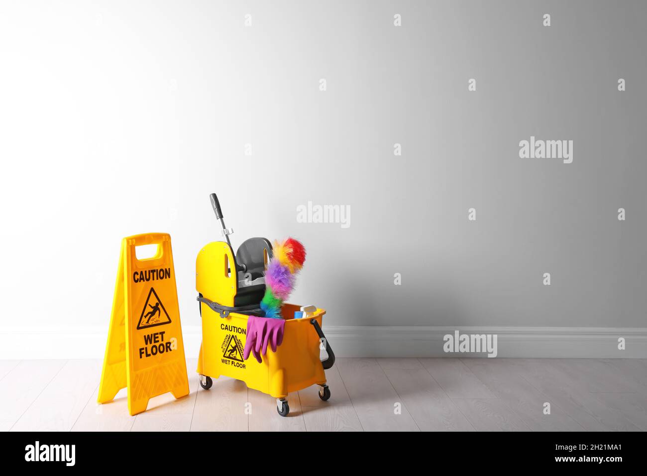 Safety sign with phrase "CAUTION WET FLOOR" and mop bucket on floor