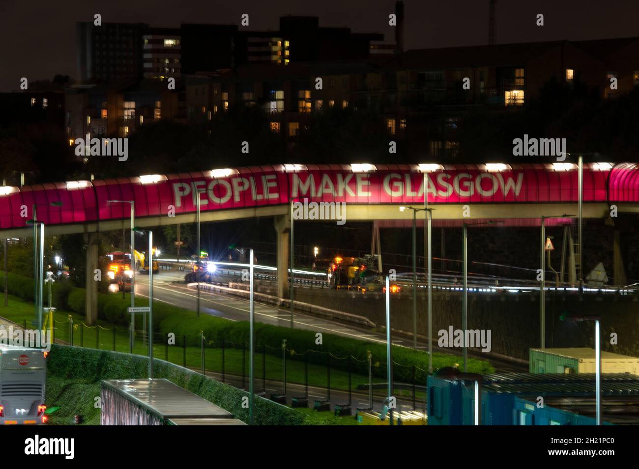 Glasgow, Scotland, UK. 19th Oct, 2021. PICTURED: People Make Glasgow walkway over the Clydeside expressway. Night views of the COP26 site and venue showing temporary structures half built on the grounds of the Scottish Event Campus (SEC) Previously known as Scottish Exhibition and Conference Centre (SECC) with the front car park outside of the newly named The OVO Hydro (formerly SSE Hydro) with new transfers over the walkway which says “People Make Glasgow” and night workers continue making preparations. Credit: Colin Fisher/Alamy Live News Stock Photo