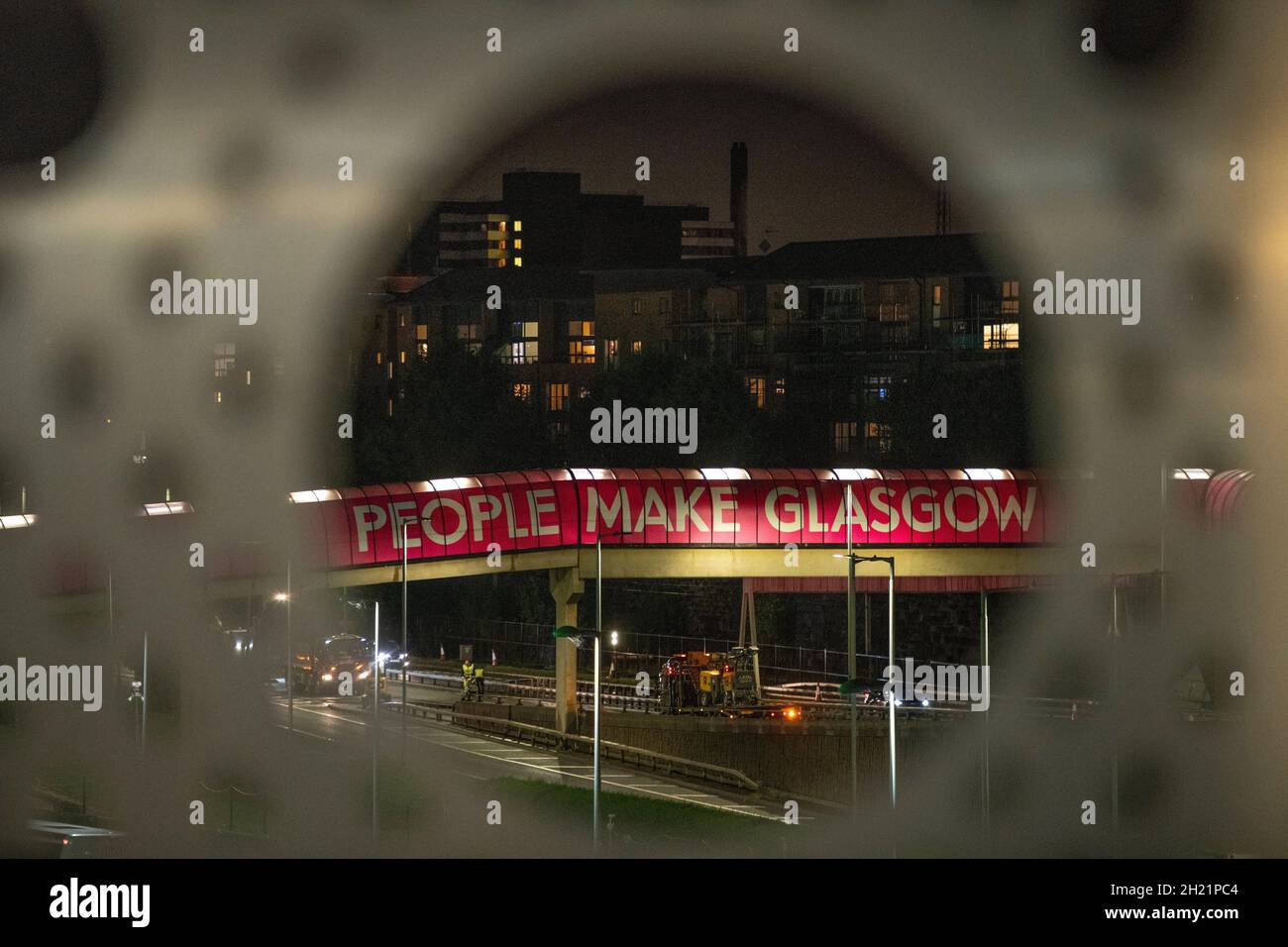 Glasgow, Scotland, UK. 19th Oct, 2021. PICTURED: People Make Glasgow walkway over the Clydeside expressway. Night views of the COP26 site and venue showing temporary structures half built on the grounds of the Scottish Event Campus (SEC) Previously known as Scottish Exhibition and Conference Centre (SECC) with the front car park outside of the newly named The OVO Hydro (formerly SSE Hydro) with new transfers over the walkway which says “People Make Glasgow” and night workers continue making preparations. Credit: Colin Fisher/Alamy Live News Stock Photo