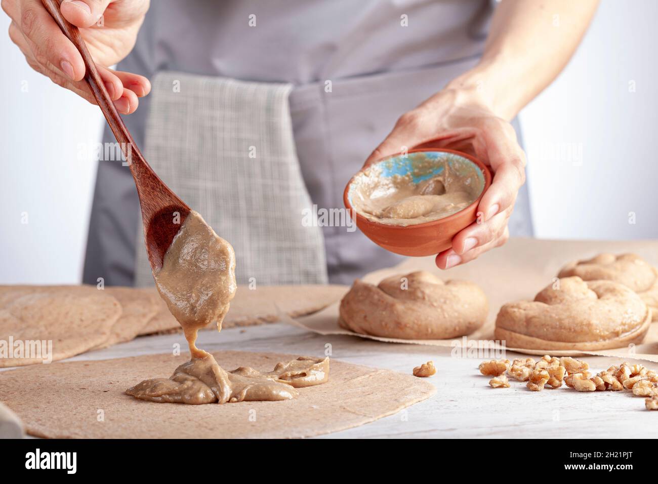 closeup isolated image of a caucasian woman preparing sweet Turkish pastry rolls with tahini and petimezi (tahin pekmez) She mixes the ingredients and Stock Photo