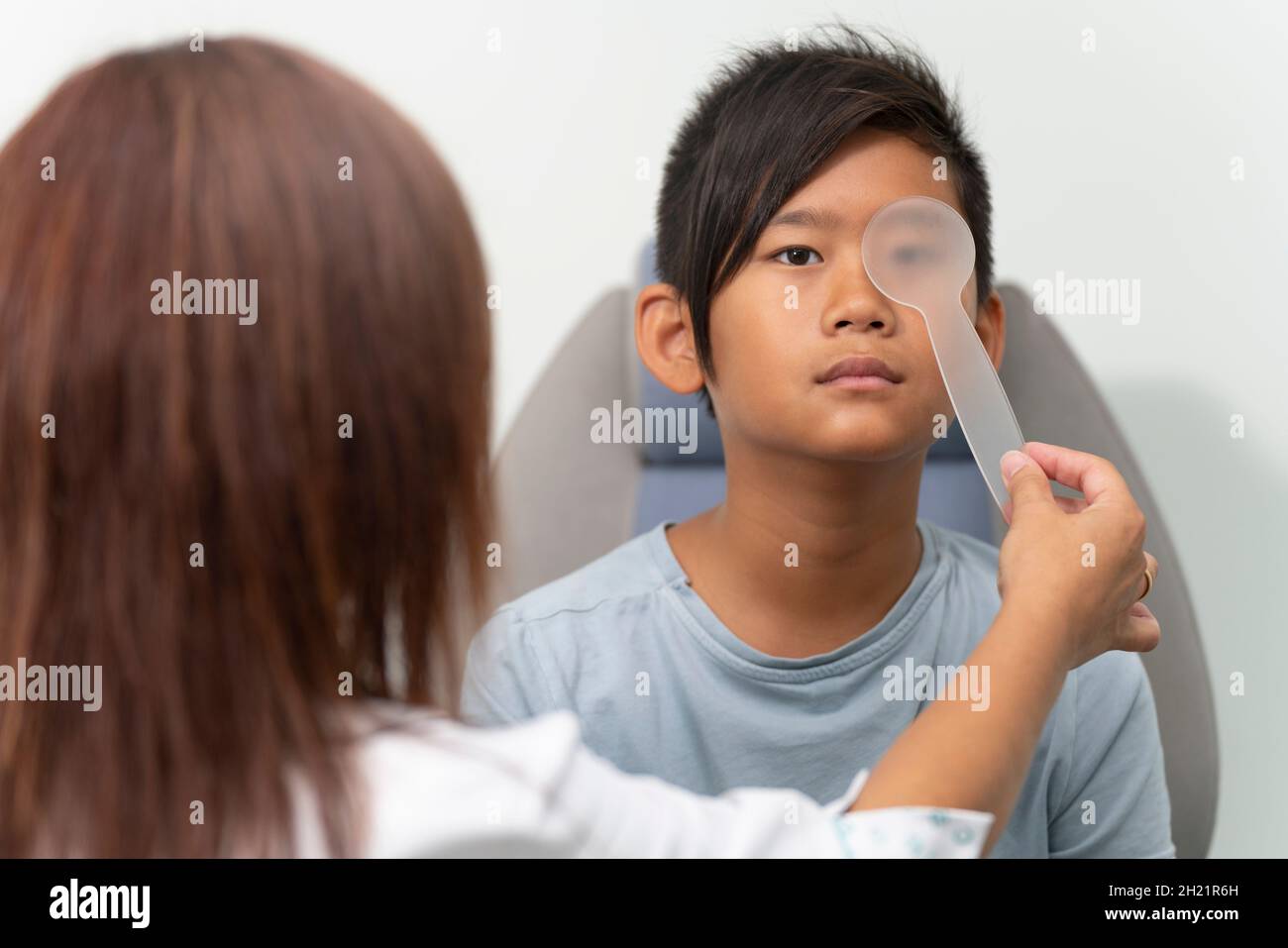 Asian boy in a consultation of an ophthalmologist woman Stock Photo
