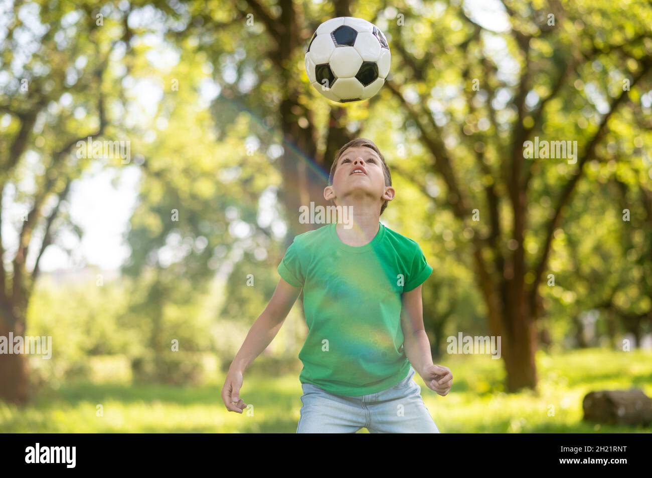 Attentive boy looking at soccer ball up in air Stock Photo Alamy