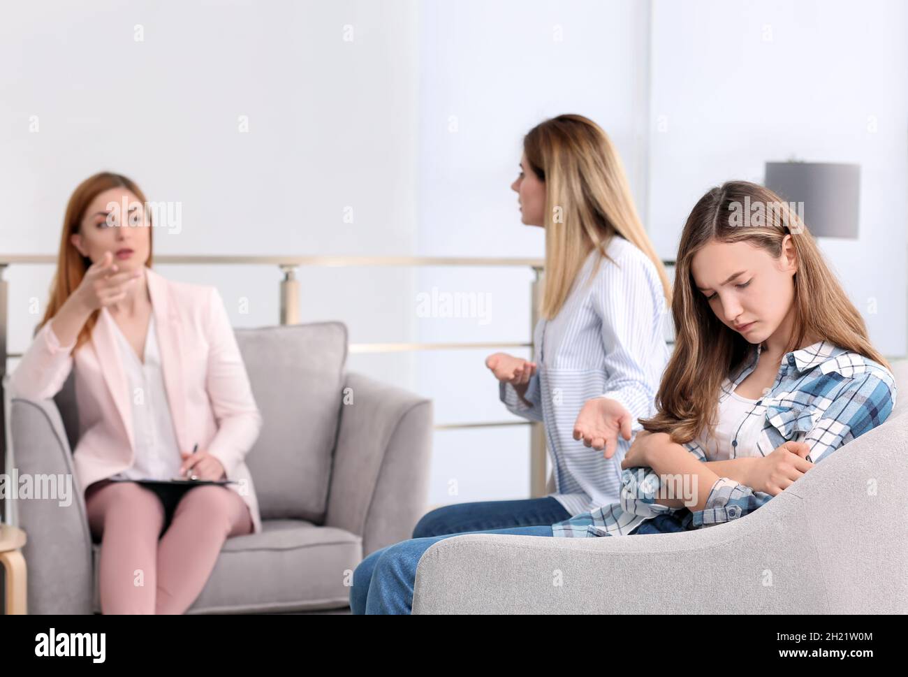 Young female psychologist working with teenage girl and her mother in
