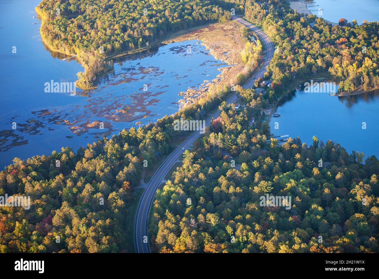 Aerial view of curving road between lakes and trees in autumn color in northern Minnesota Stock Photo