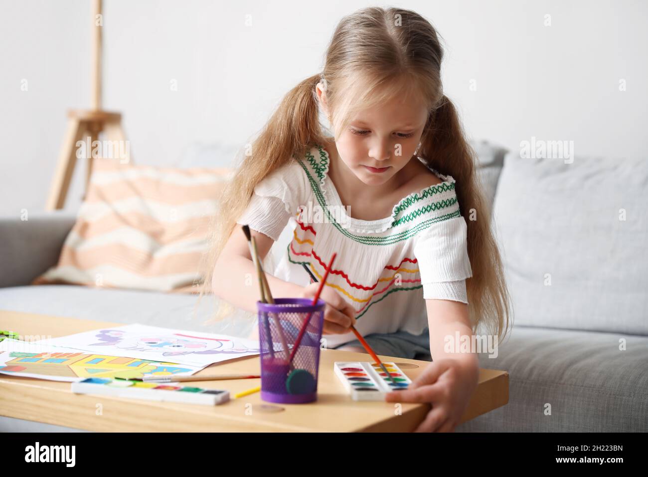 Little girl painting with watercolors at table Stock Photo - Alamy