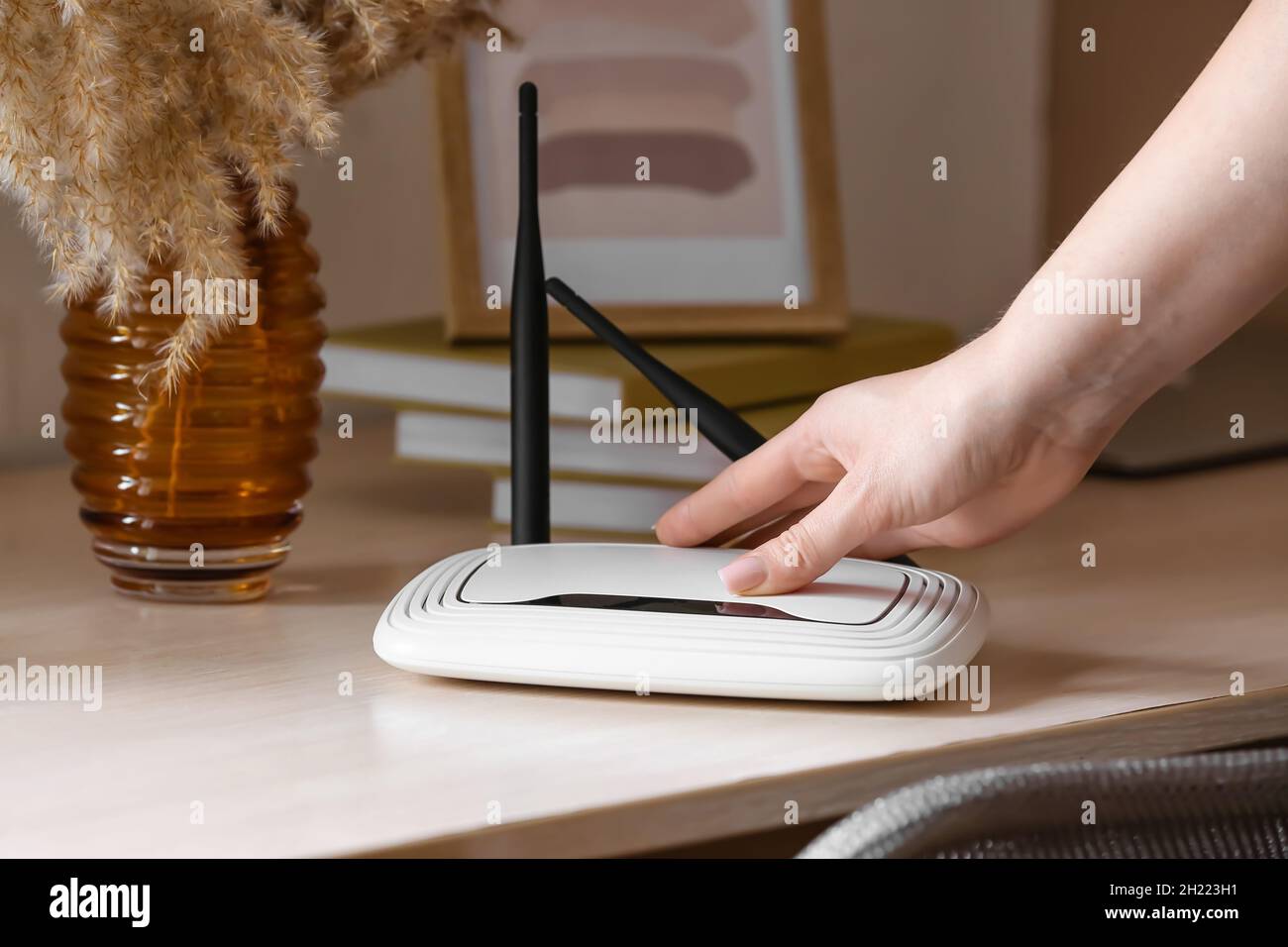 Female hand with wi-fi router on table in room Stock Photo - Alamy