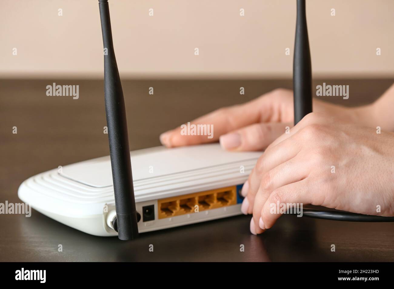Woman inserting ethernet wire into wi-fi router on table in room Stock ...