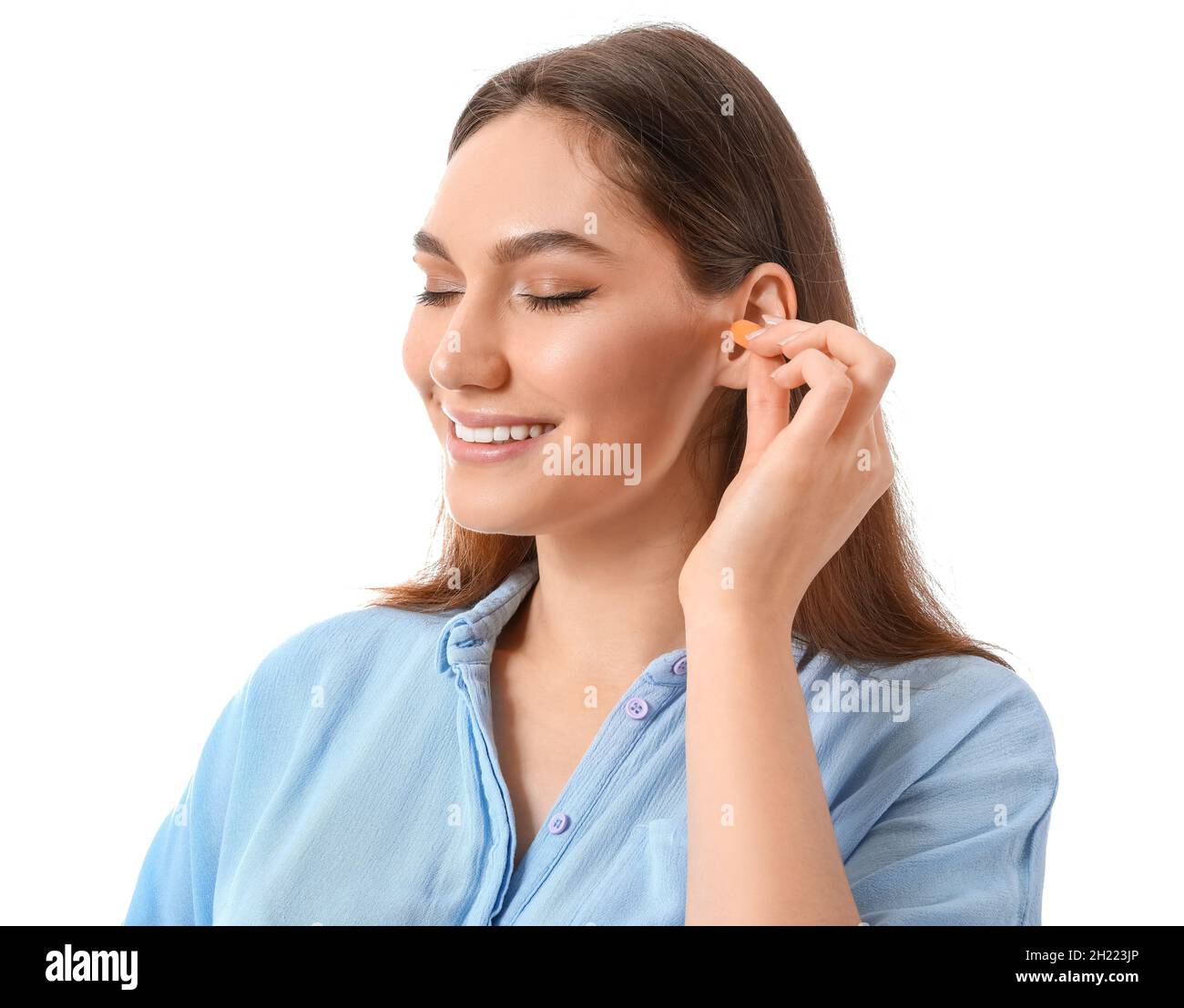 Young woman inserting earplugs on white background Stock Photo Alamy