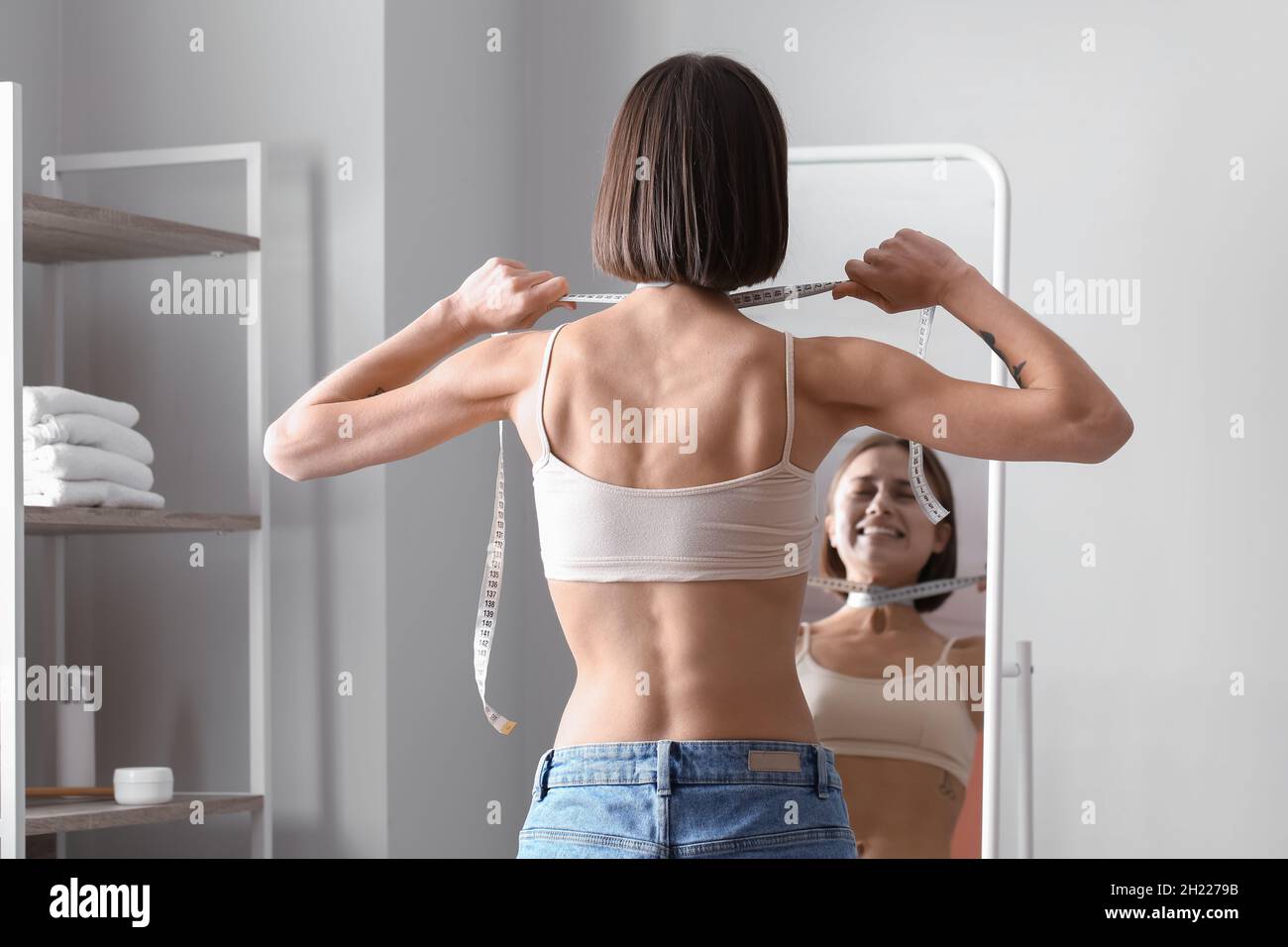 Young skinny woman in front of mirror at home. Anorexia concept Stock Photo