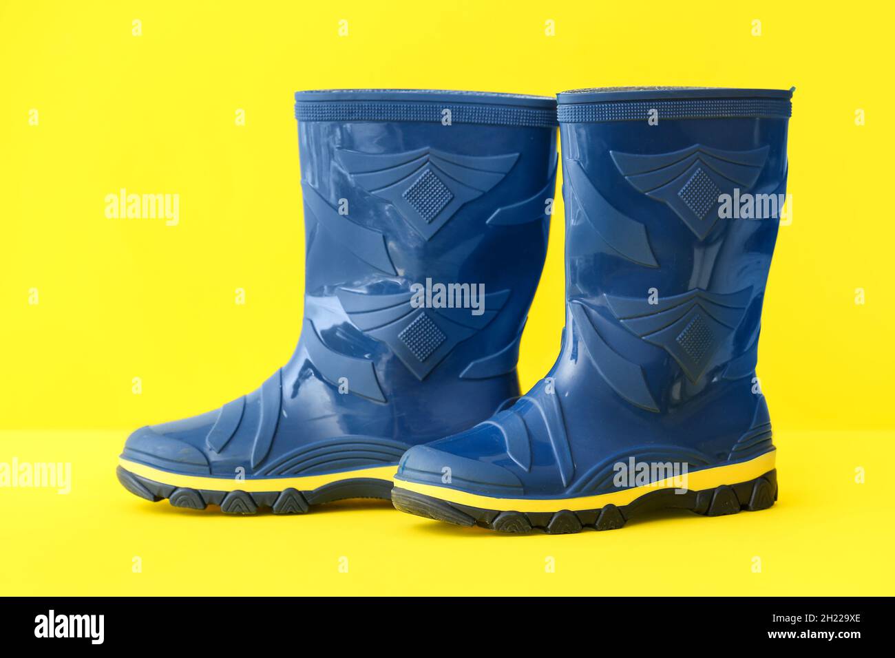 Pair of blue rubber boots on yellow background Stock Photo - Alamy