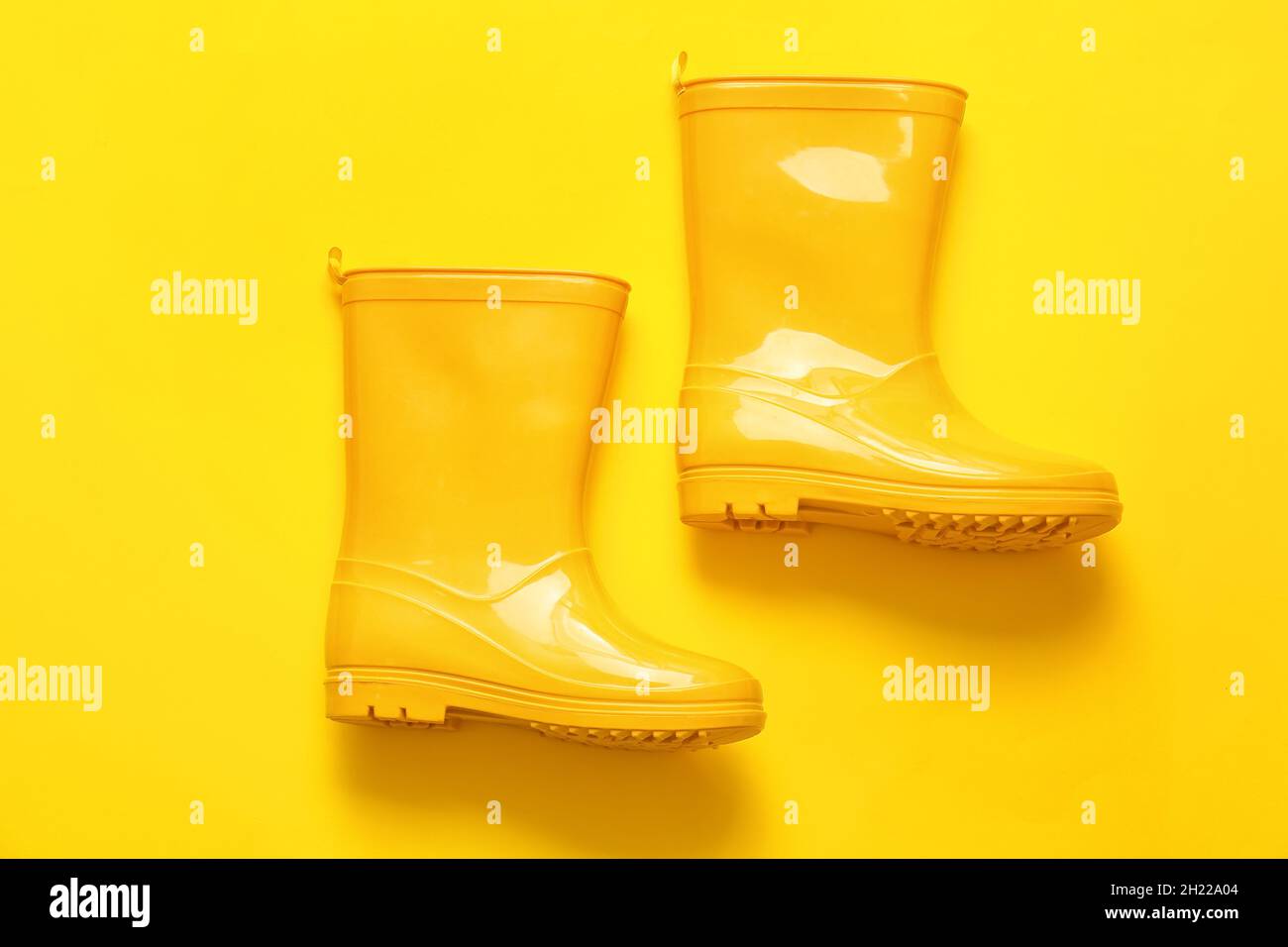 Pair of rubber boots on yellow background Stock Photo - Alamy