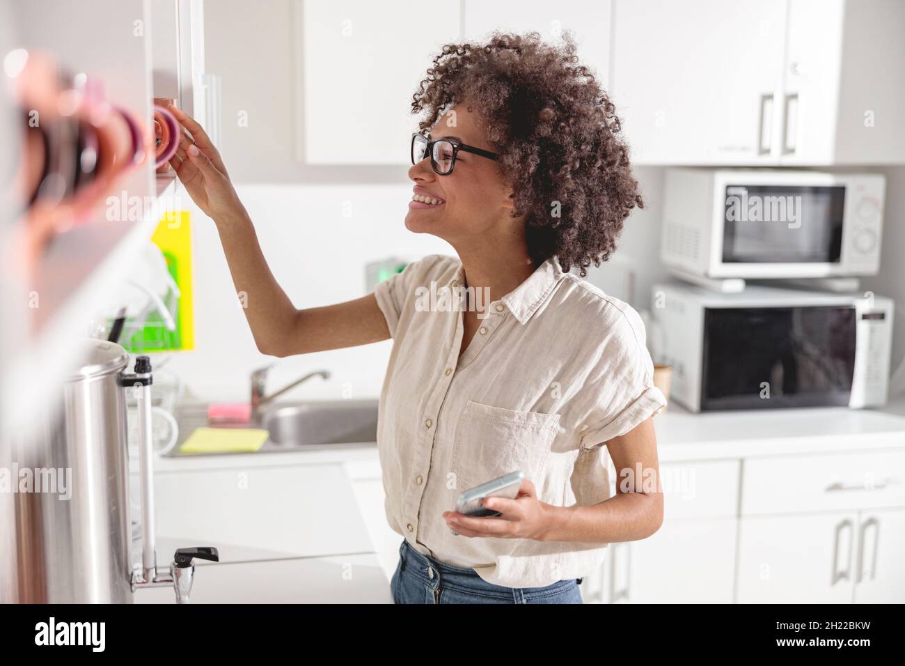 Happy Afro American lady taking a cup off the shelf Stock Photo
