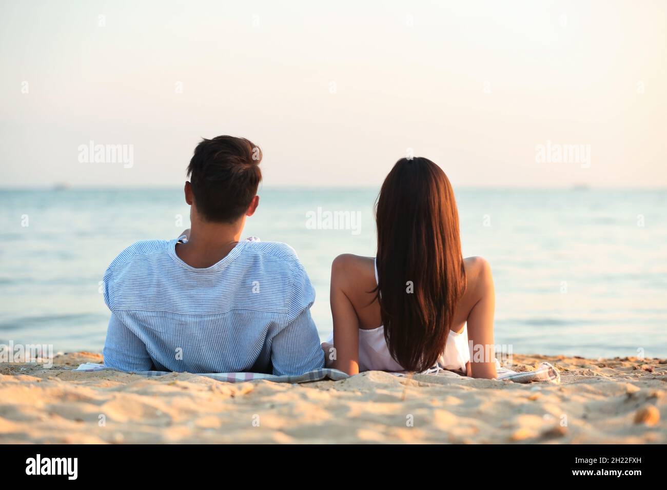 Happy young couple lying together on beach Stock Photo - Alamy