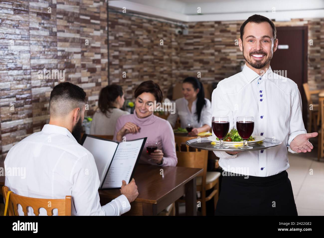 Waiter welcoming guests in restaurant Stock Photo - Alamy