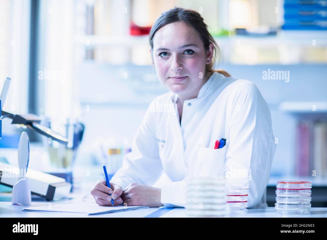 Young lab technician with sample on petridish working in a lab with lab