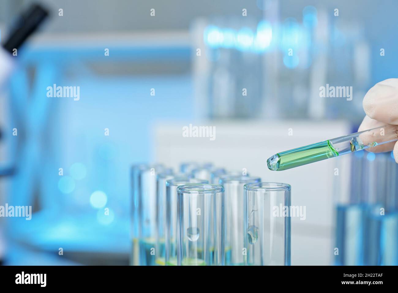 Analyst dripping reagent into test tube with sample at laboratory