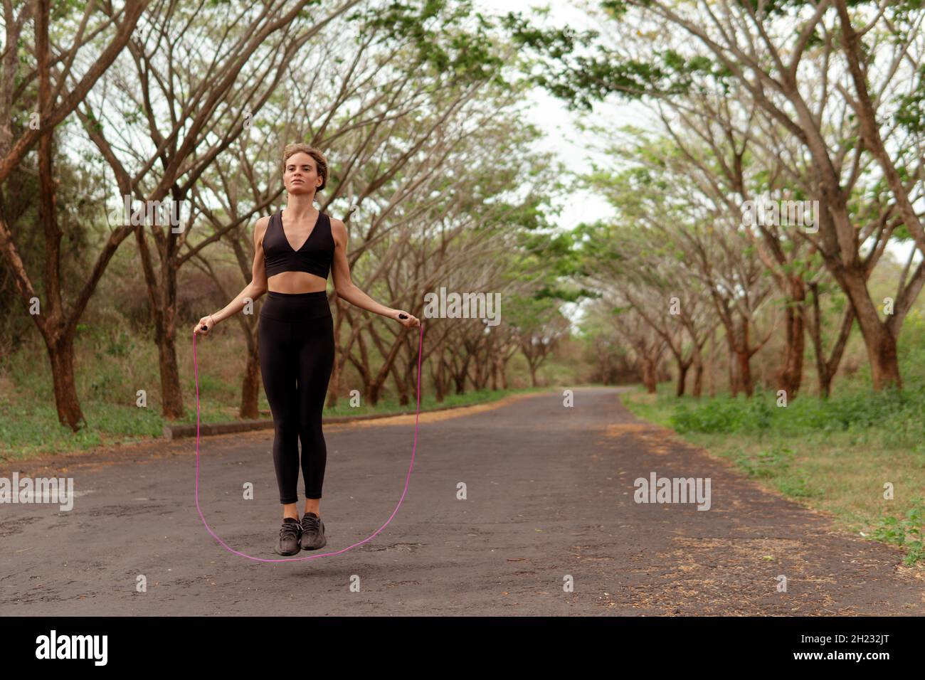 Lady Jump Rope woman jumping rope in black sportwear. bali Stock Photo - Alamy