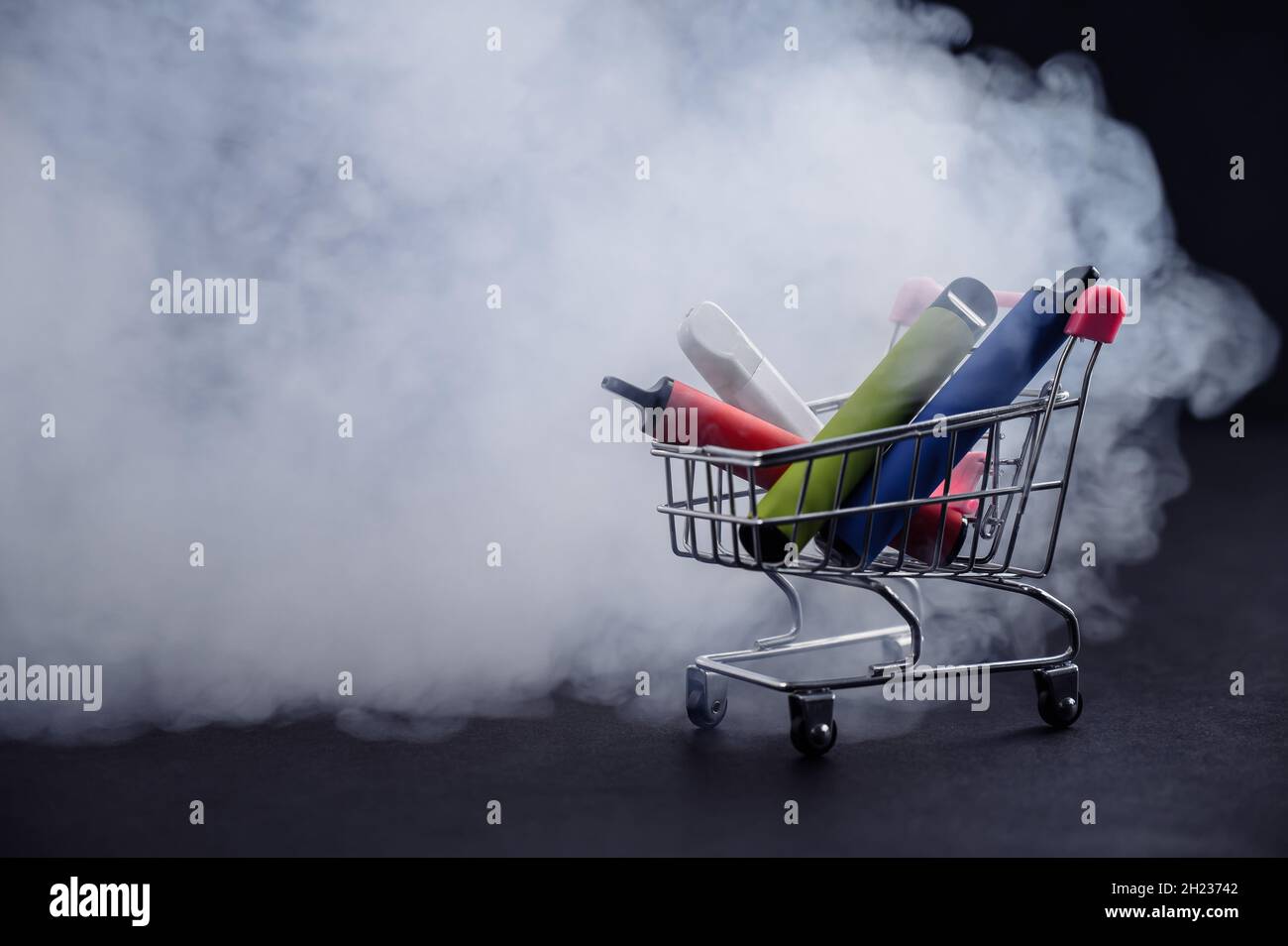 Disposable vapes in a shopping cart on a black background. Modern electronic cigarettes. Stock Photo