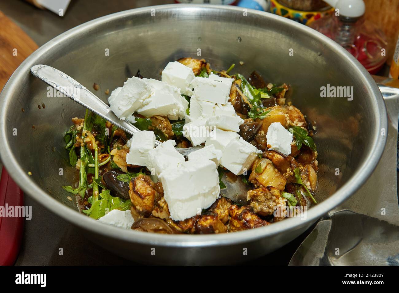 Feta cheese, baked eggplant and arugula in salad bowl. Step by step recipe Stock Photo