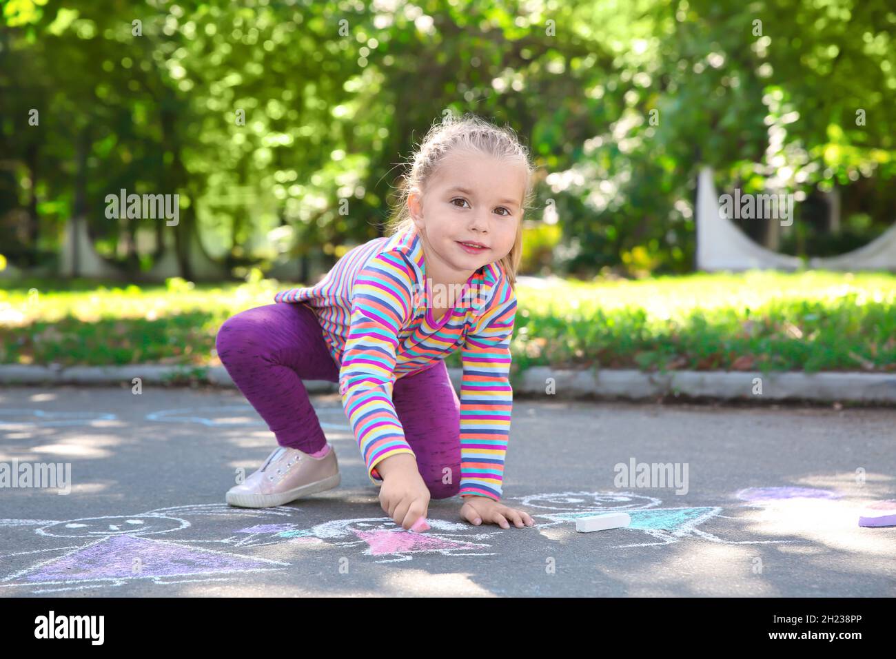 Little child drawing with colorful chalk on asphalt Stock Photo - Alamy