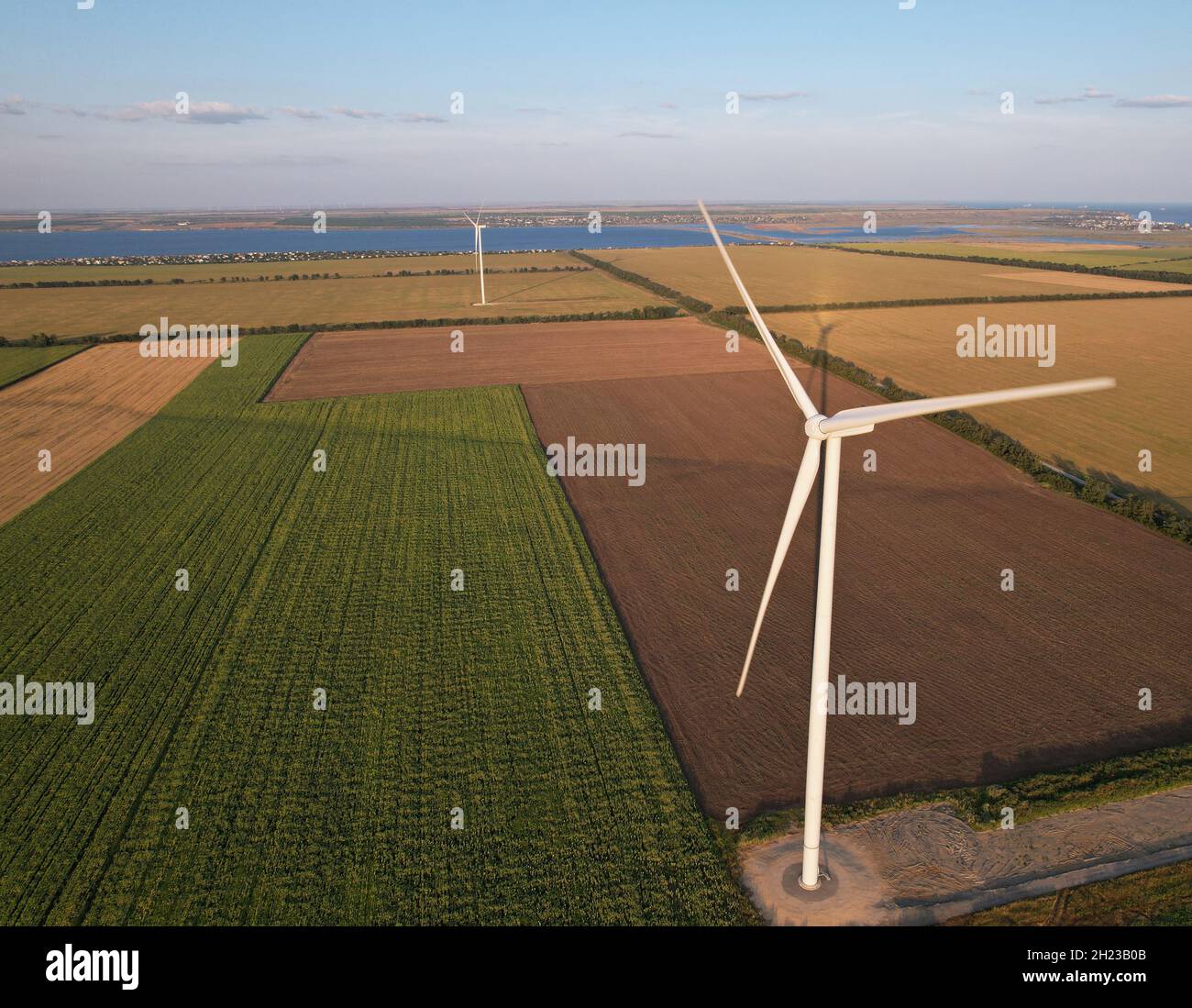 Wind turbine on farmland against the background of the sea. Stock Photo