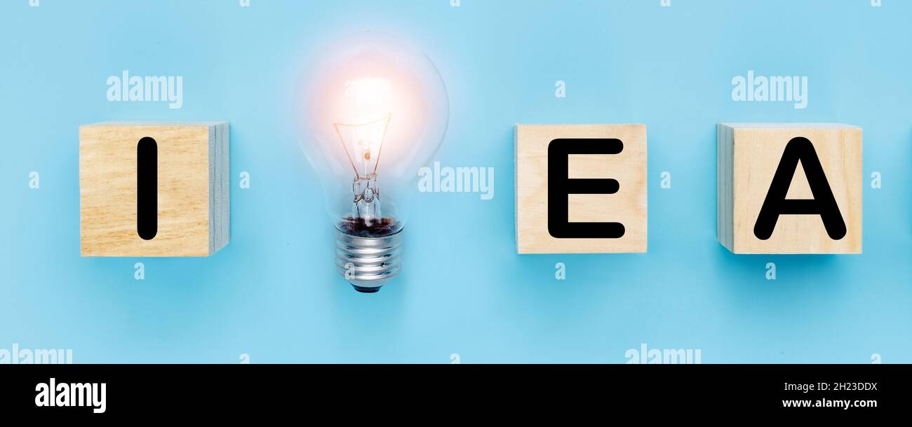 idea and new creative thinking concept, light bulb with idea word on wood block on blue background Stock Photo