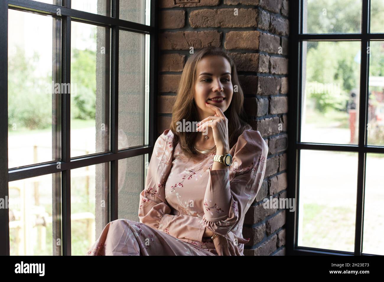 Beautiful young woman in pink dress sits on the windowsill Stock Photo ...