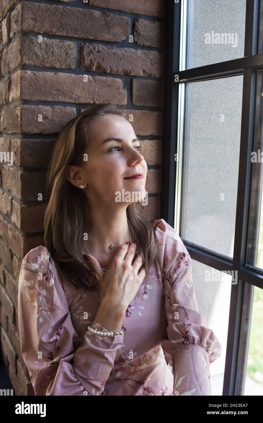 Beautiful young woman in pink dress sits on the windowsill Stock Photo ...