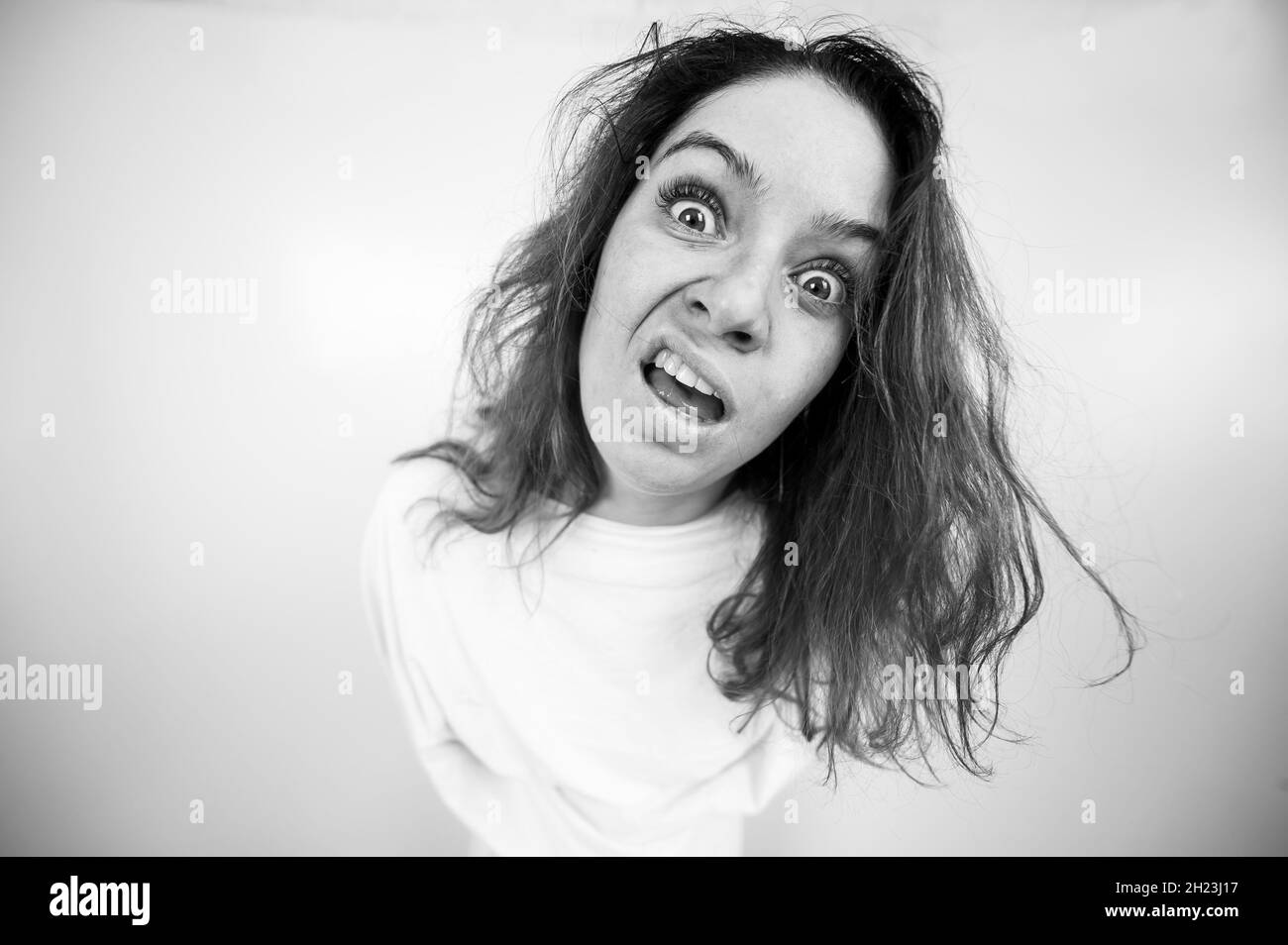 Close-up portrait of insane woman in straitjacket on white background. Monochrome. Stock Photo
