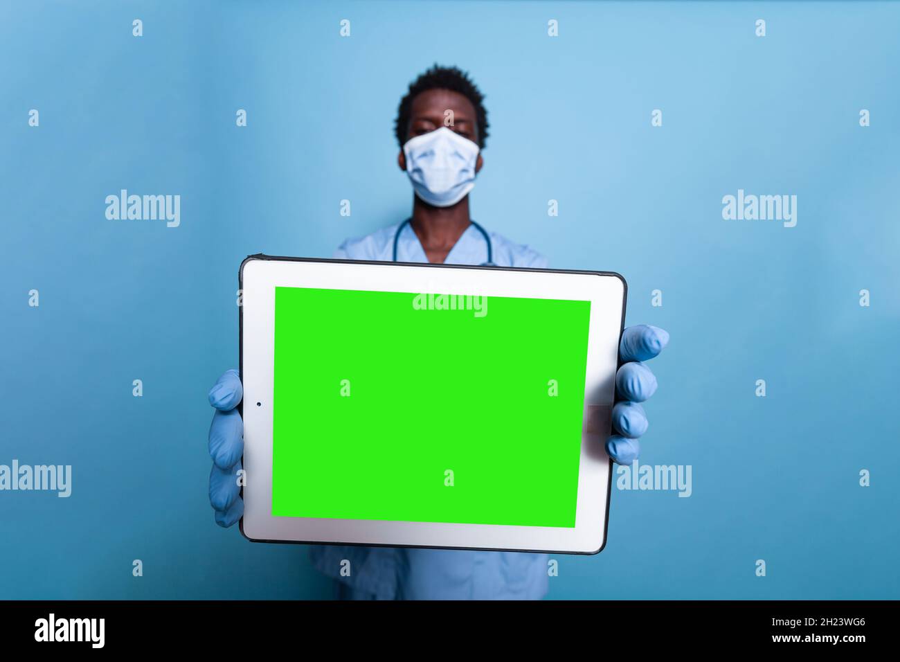 Healthcare assistant showing tablet with horizontal green screen. Medical  nurse with face mask, gloves and stethoscope holding gadget with chroma key  and mockup template for isolated background Stock Photo - Alamy