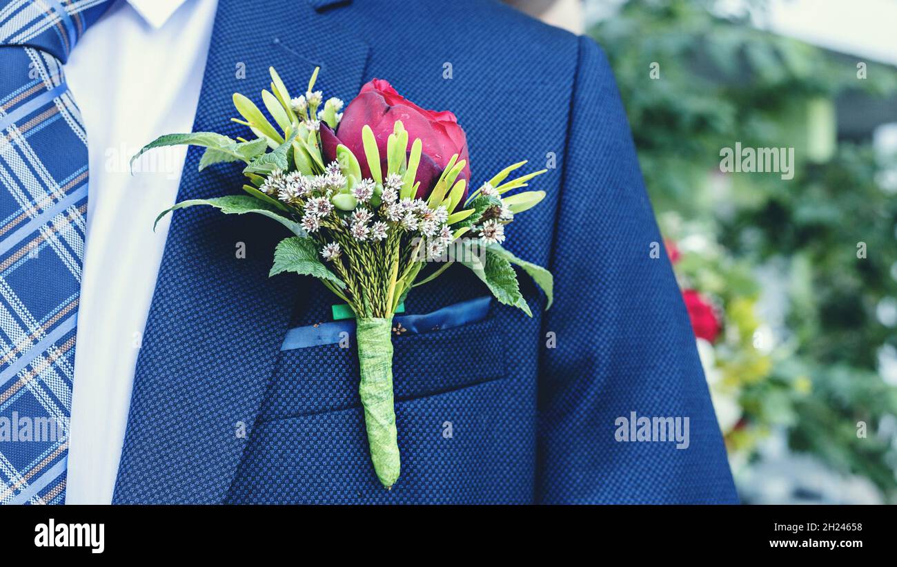 Close-up wedding boutonniere of the groom on a blue suit. Wedding floristry. Ready for wedding ceremony. Blur background. Stock Photo