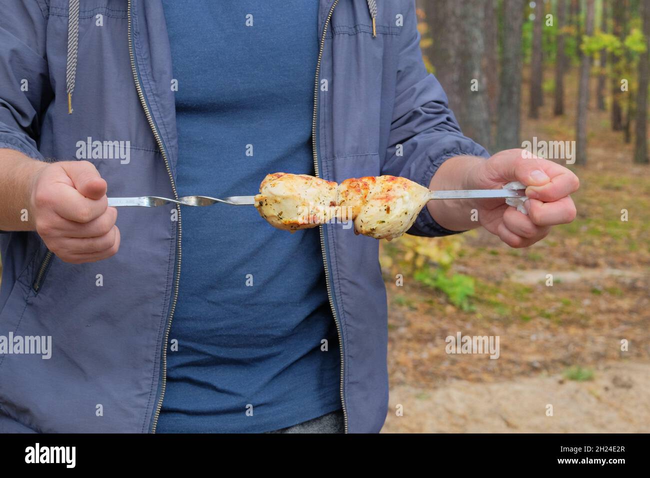 Grilled meat in the hands of a man in nature. Shish kebab frying on
