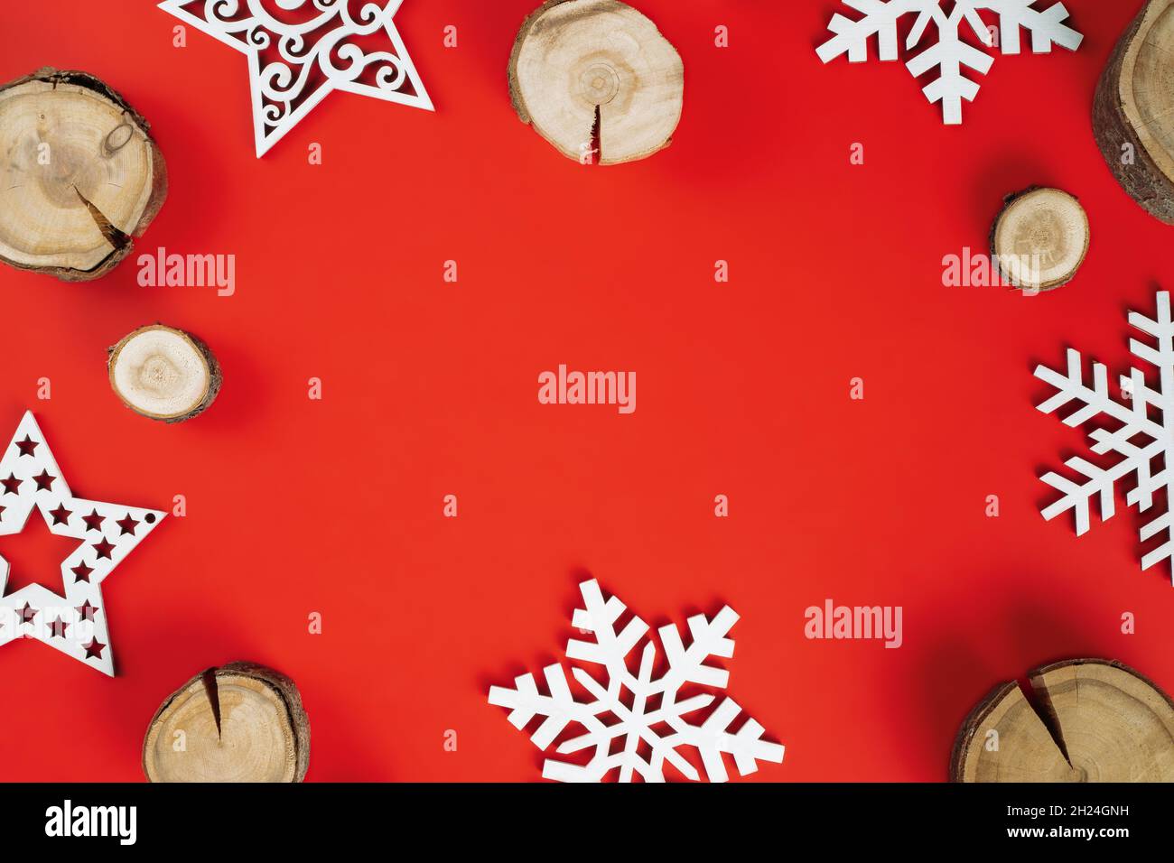 Wood cuts or branch slabs and wooden snowflakes on red background. Christmas or New Year concept. Flat lay. Copy space Stock Photo