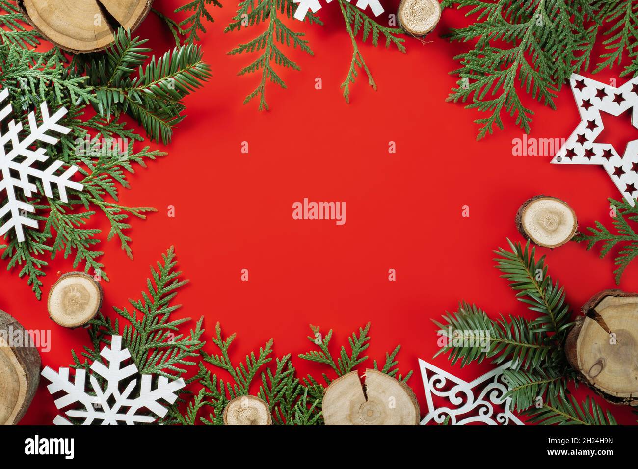 Wood cuts or branch slabs and wooden snowflakes with Christmas tree branches on red background. Christmas or New Year concept. Flat lay. Copy space Stock Photo