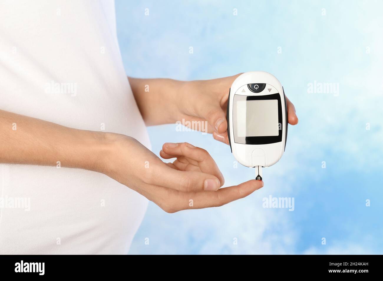 Pregnant woman checking blood sugar level with on color background. Diabetes test