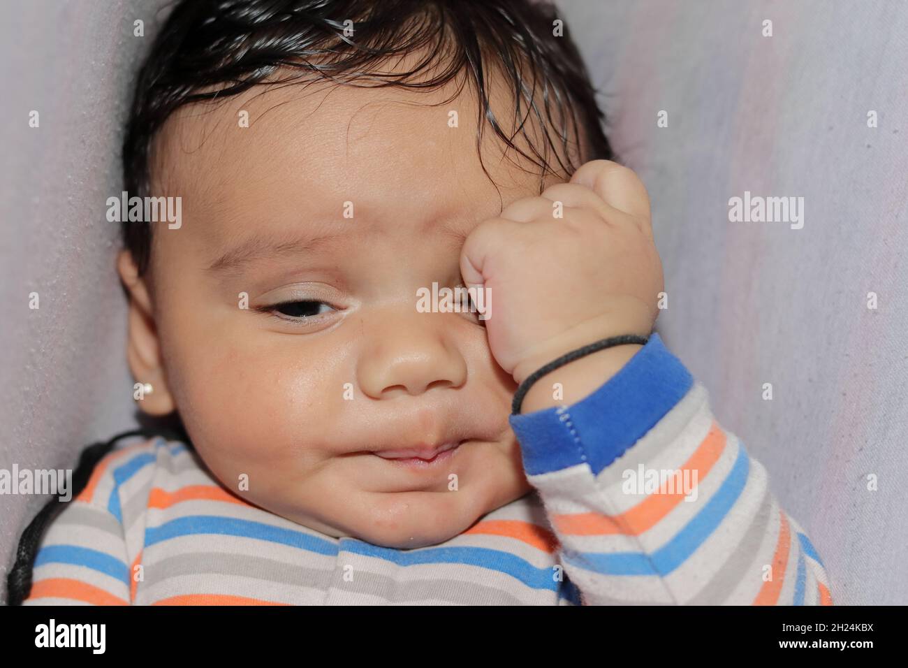 Close-up of An indian little newborn innocent baby upset and in a sad mood with white background Stock Photo