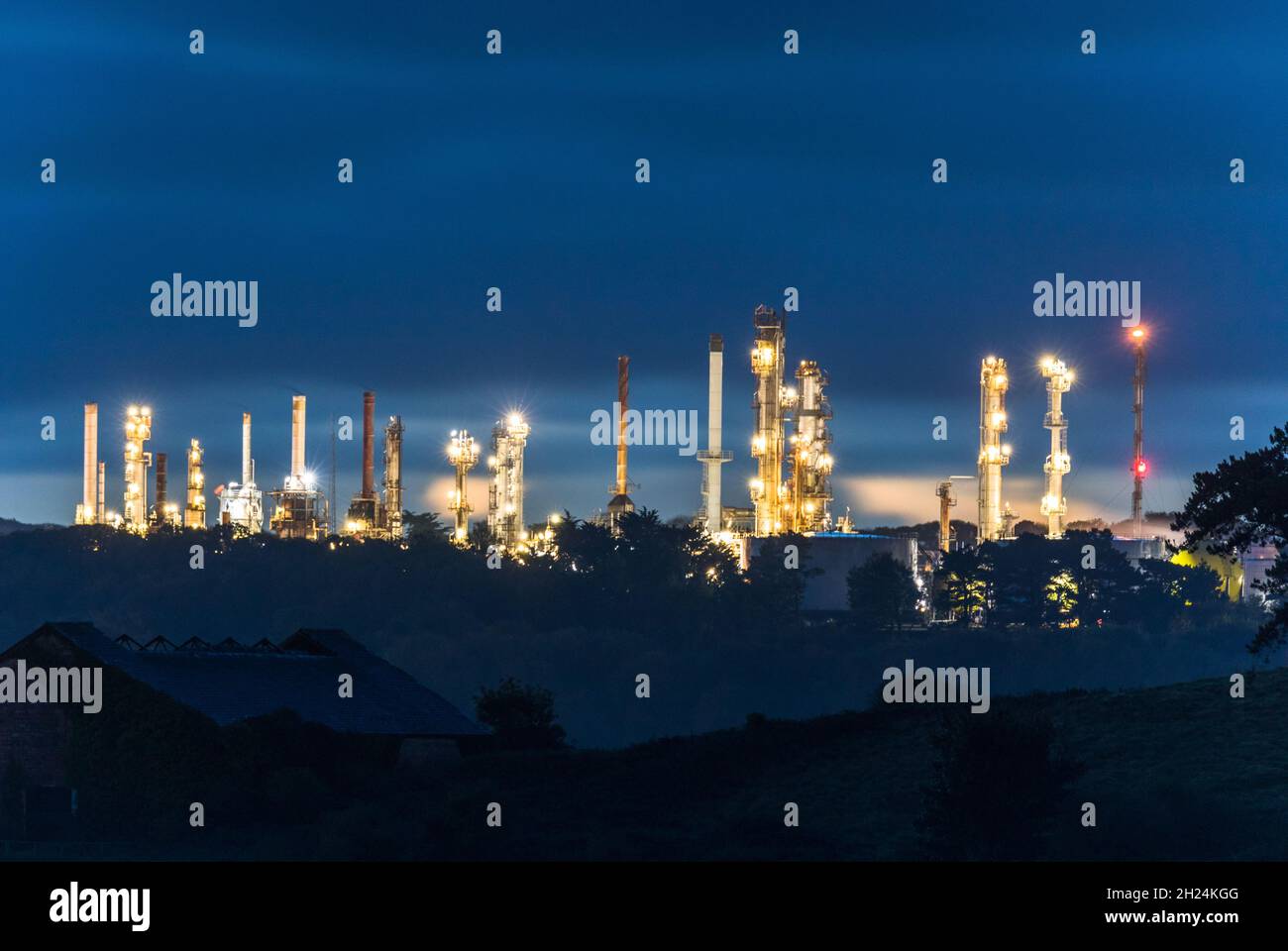 Whitegate, Cork, Ireland. 20th October, 2021. Distillation towers from the oil refinery illuminate around the harbour during blue hour at Whitegate Co. Cork, Ireland. - Picture; David Creedon  / Alamy Live News Stock Photo