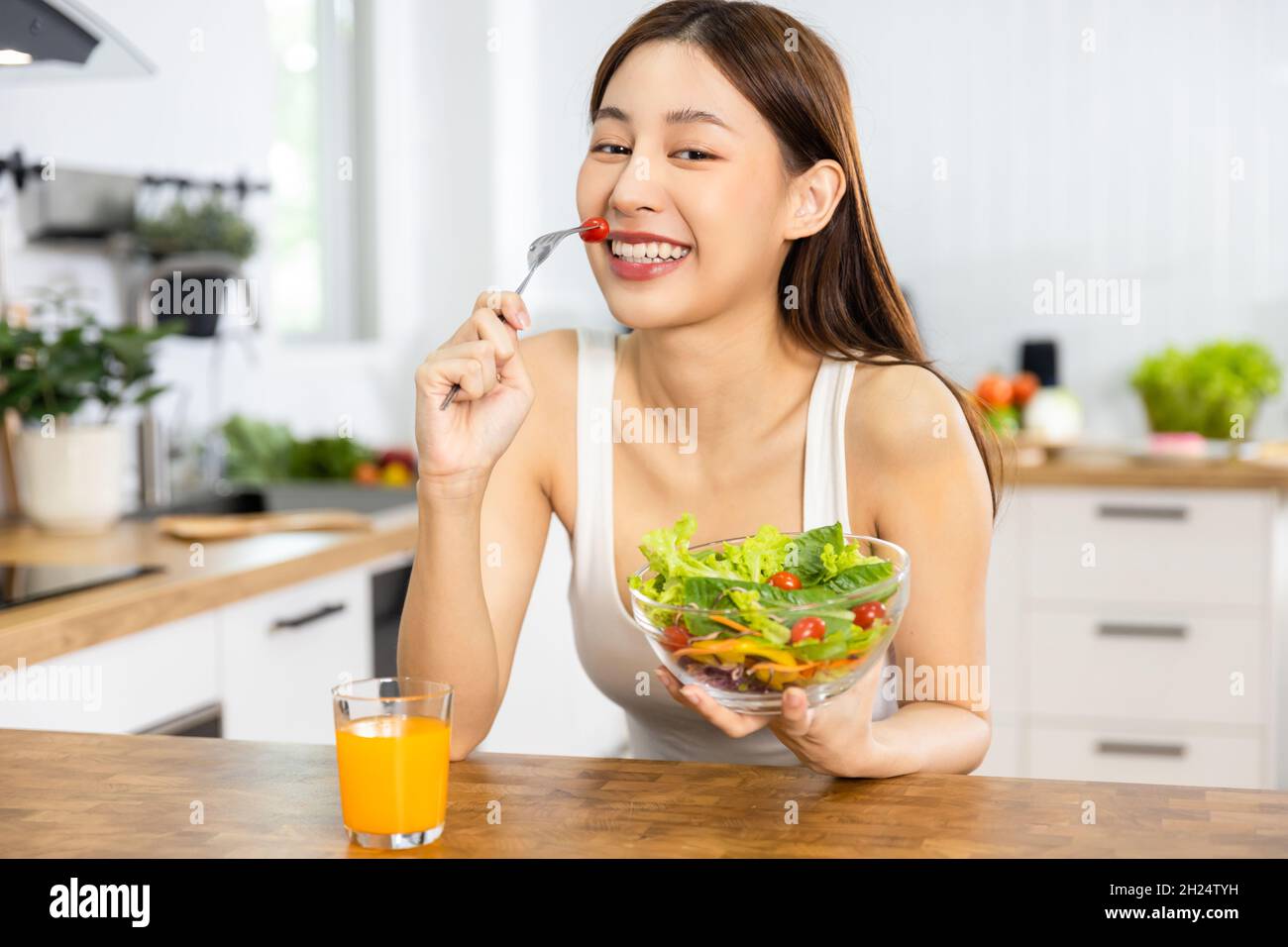 Close up Happy Asian healthy woman smiled and holding  vegetable salad and eat small tomato to diet and eat clean food Stock Photo
